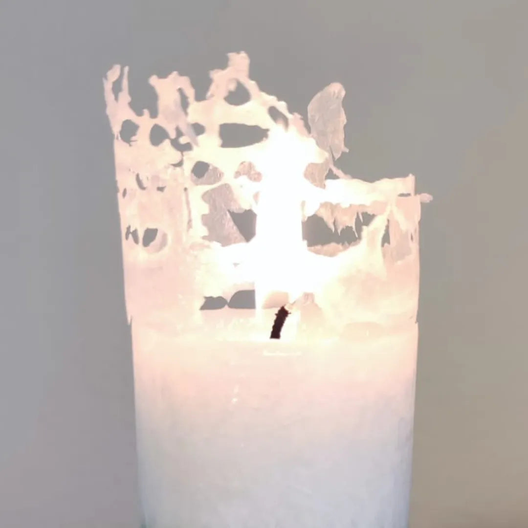 Nahaufnahme einer brennenden weißen Kerze mit leuchtendem, filigranem Abbrand-Rand.