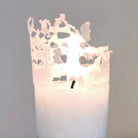 Nahaufnahme einer brennenden weißen Kerze mit leuchtendem, filigranem Abbrand-Rand.