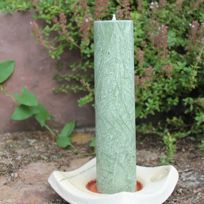 Dunkelgrüne Kräuterkerze "Ahnen" auf Kerzenteller, stärkt Verbindung zu Vorfahren & hilft alte Muster zu erkennen.