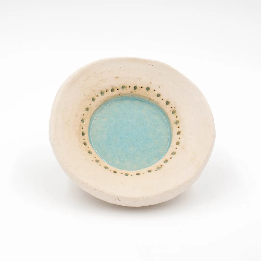 Handgetöpferter Kerzenteller aus dem Allgäu mit türkis-farbener Glasur und Lochprägung, von oben.