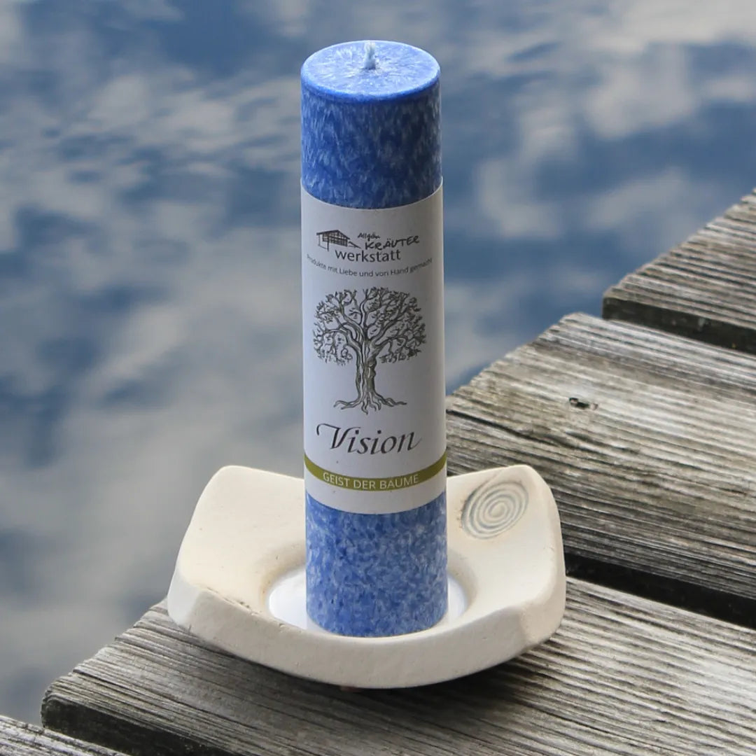 Blaue Kräuterkerze "Vision" auf Holzsteg am Wasser, schenkt Stabilität & Klarheit für persönliches Wachstum.