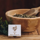 Holzbox "Allgäuer Räucherwerk Weisheit" mit Dachs-Motiv neben Kräuterschale.