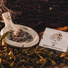 Stimmungsvolle Präsentation des Allgäuer Räucherwerks "Schutz" mit Igel-Box und rauchender Schale in natürlicher Umgebung.