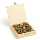 Geöffnete Holzbox "Allgäuer Räucherwerk Seelenzauber Stille" mit Räuchermischung und Rosenblüten.