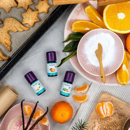 Baldini Bio Öle: Orange, Vanille, Mandarine in Backumgebung mit Orangen und Gebäck.