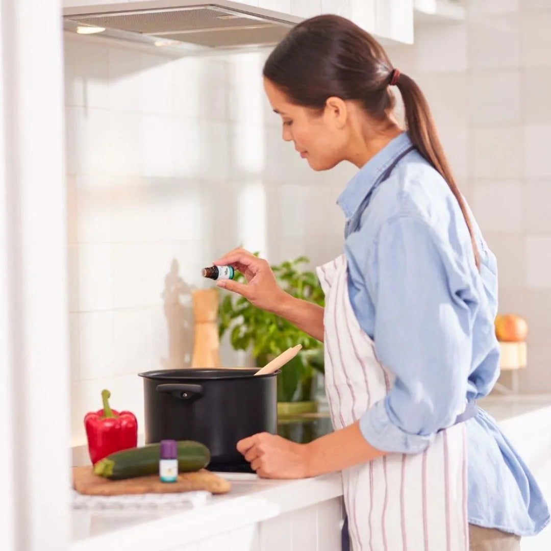 Frau kocht und verwendet Baldini Bio Rosmarinöl, ideal für kulinarische Genüsse.