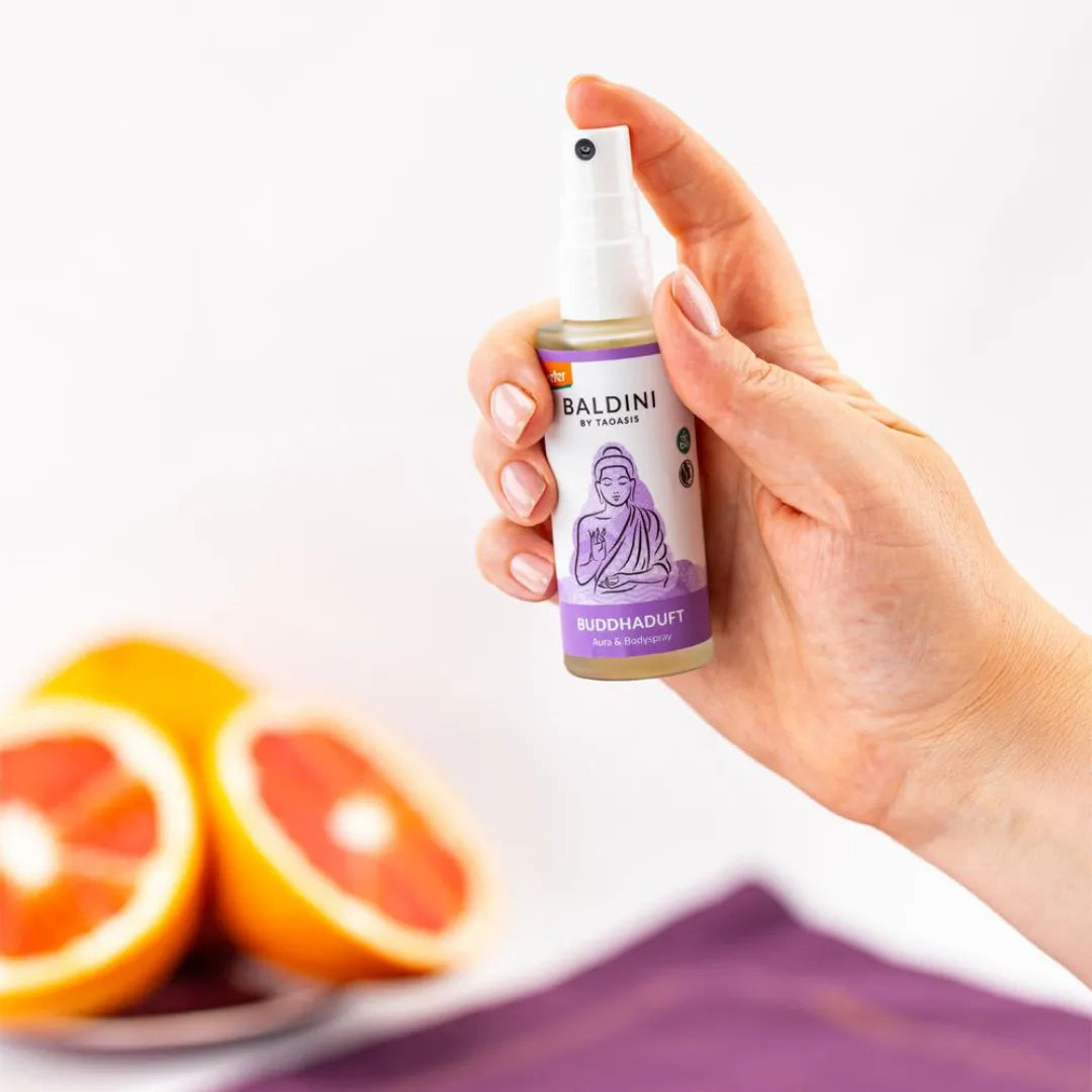 Hand hält Baldini Buddhaduft Aura & Bodyspray, harmonisierend und entspannend, mit Grapefruits.