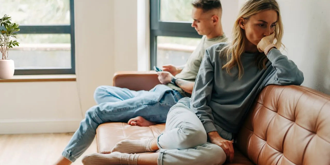 Ein Paar sitzt abgewandt von einander auf der Couch, die Stimmung ist sehr angespannt.