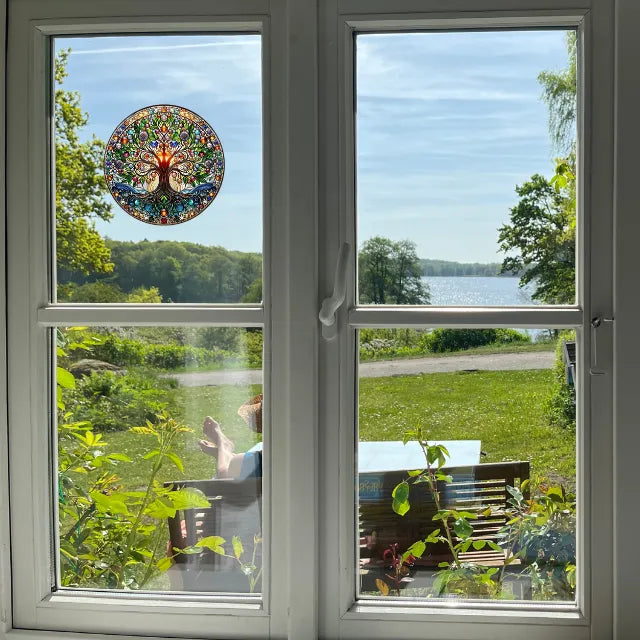 Bunter Fensteraufkleber Baum des Lebens auf Fenster mit Blick auf See und grüne Landschaft, ideal als Sonnenfänger für Wohnräume.