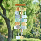 Muschelwindspiel hellblau-gelb-braun im Garten, Capiz-Mobile für entspannte Atmosphäre.
