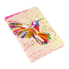 Buntes A5 Notizbuch 'Flower' mit abstraktem Kolibri-Motiv und Goldprägung, leicht geöffnet.