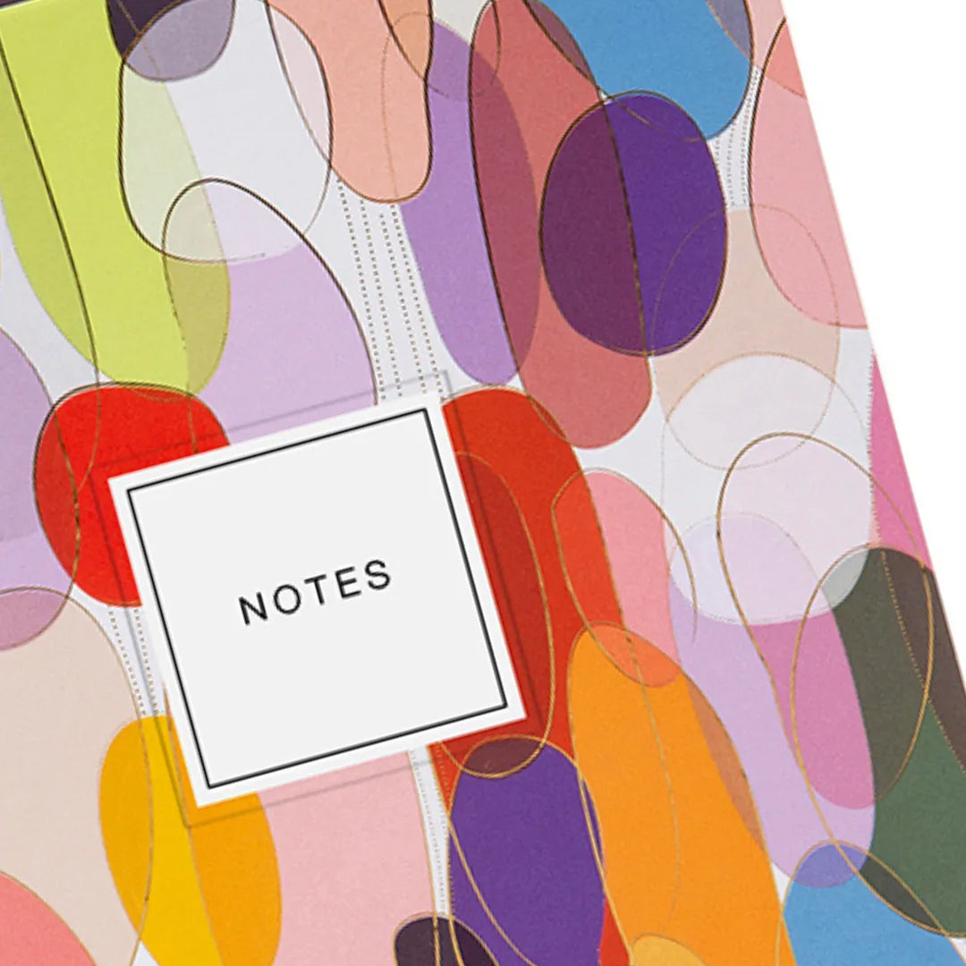 Nahaufnahme des bunten A5 Notizbuchs 'Urban Optimistic' mit Goldprägung und 'NOTES' Label.