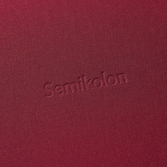 Detailansicht des bordeauxroten Semikolon Notizbuchs A5 mit geprägtem 'Semikolon' Schriftzug.