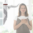 Windspiel mit spiralförmigen Röhren und Notenlinien, symbolisiert Ruhe und Entspannung bei meditierender Frau.