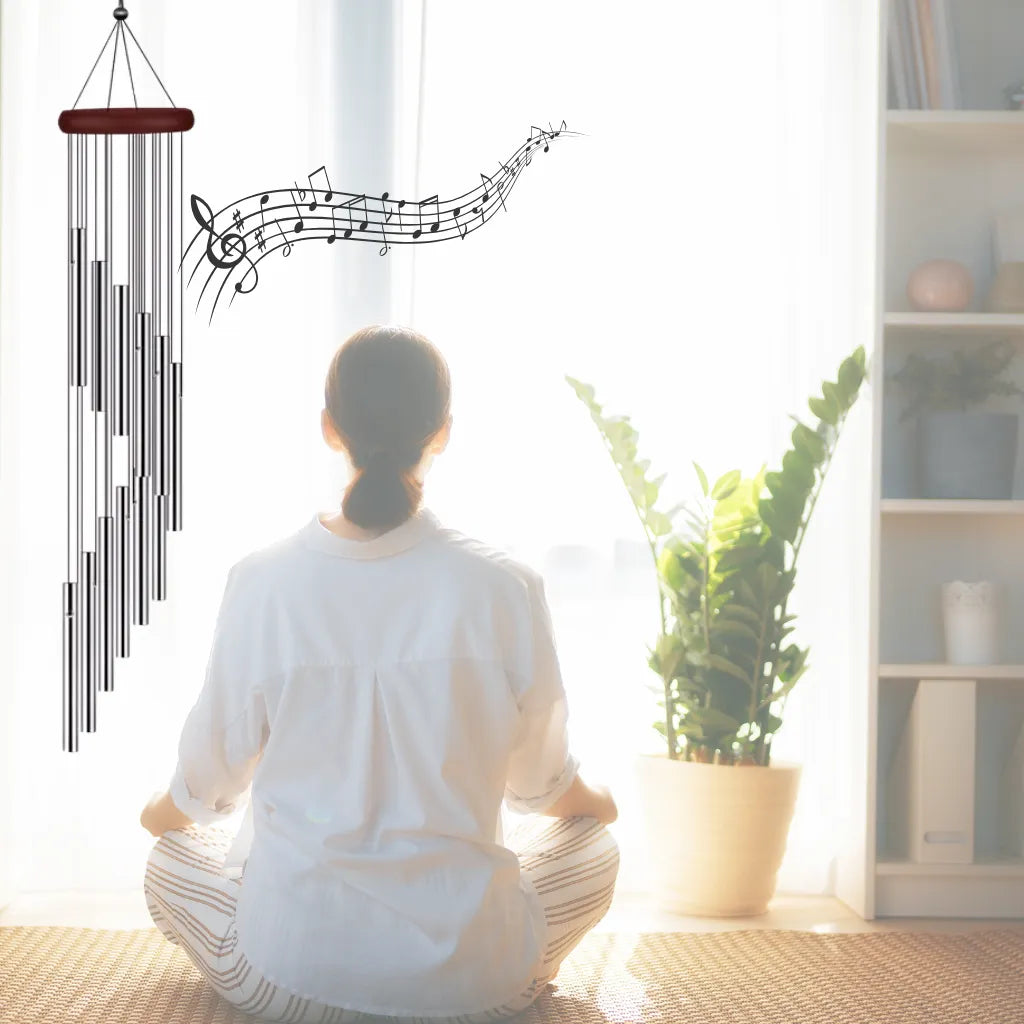 Windspiel mit spiralförmigen Röhren und Notenlinien, symbolisiert Frieden und Harmonie bei meditierender Frau.