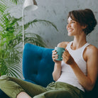 Frau entspannt auf Sessel mit Tasse, symbolisiert innere Balance, Ruhe und Harmonie im Alltag.