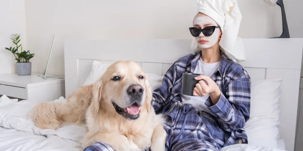 Frau entspannt mit Hund im Bett genießt Selfcare und Me-Time