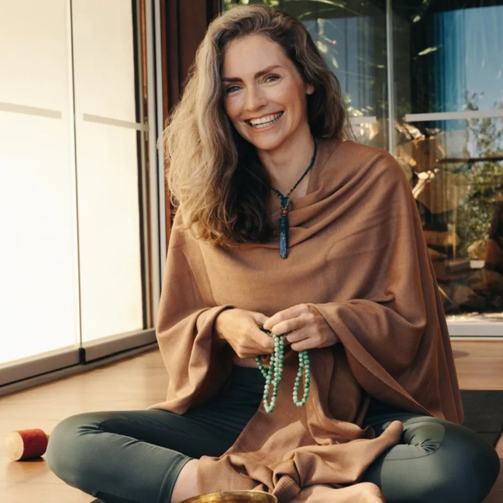 Frau mit Gebetskette lächelt, symbolisiert Achtsamkeit, positives Karma und innere Klarheit.