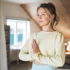 Frau meditiert in Gebetshaltung, symbolisiert inneren Frieden, Ruhe & emotionale Balance durch Meditation.