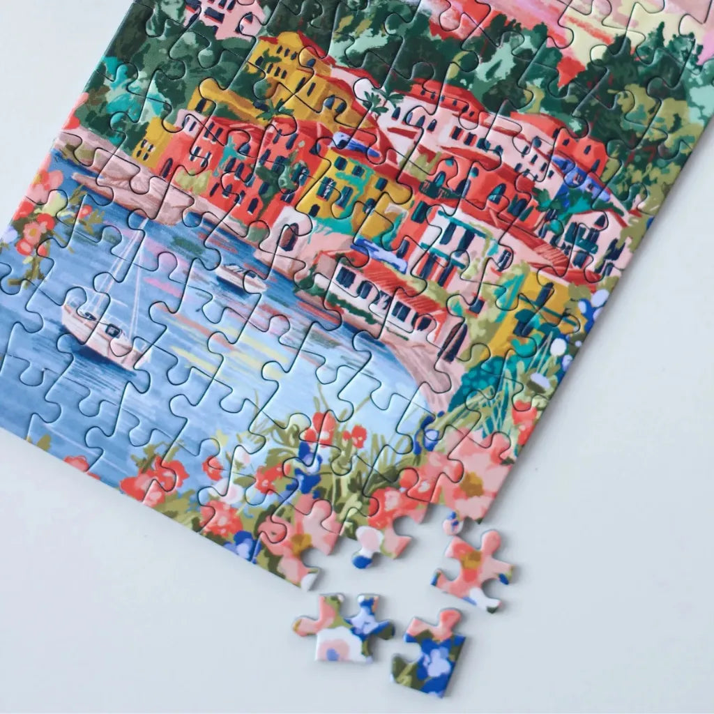 Nahaufnahme eines teilweise gelegten 99 Teile Piecely Minipuzzles "Lake Como" mit losen Puzzleteilen. Zeigt die lebendigen Farben der Häuser, des Sees und der Blumen.
