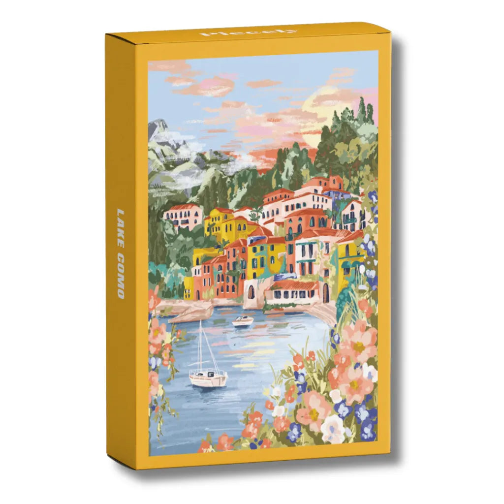 Piecely Minipuzzle 99 Teile "Lake Como" Produktverpackung. Zeigt eine farbenfrohe Illustration des Comer Sees mit bunten Häusern, Bergen, einem Segelboot und blühenden Pflanzen.