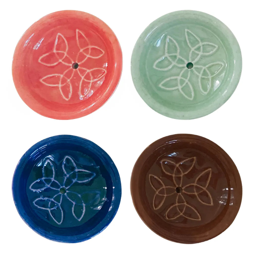 Vier runde Keramik Räucherstäbchenhalter in Korallrot, Mintgrün, Königsblau und Dunkelbraun, jeweils mit einem harmonischen weißen Knotenmuster und zentralem Loch, auf weißem Hintergrund präsentiert.