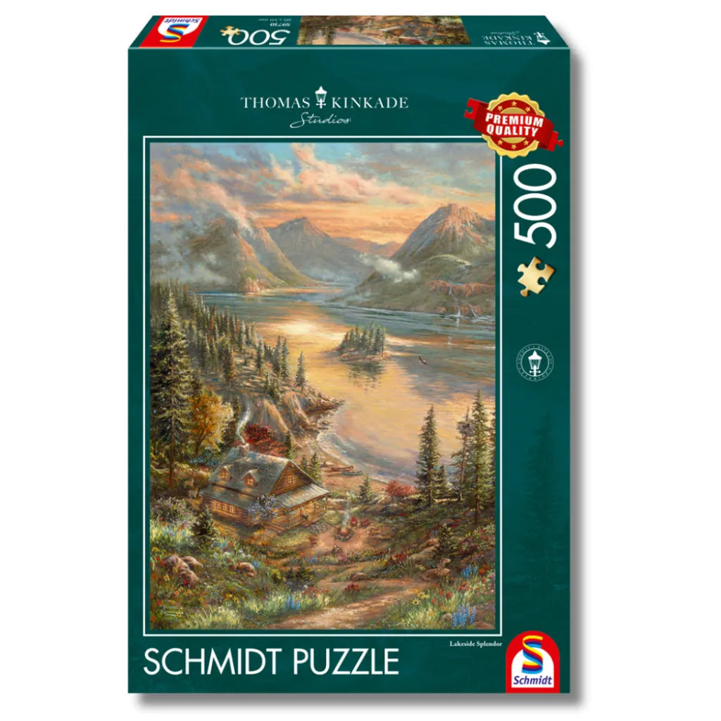 Schmidt Puzzle 500 Teile "Pracht am Seeufer" von Thomas Kinkade. Produktverpackung mit idyllischer Seeuferlandschaft, gemütlicher Hütte, Bergen und goldener Abendstimmung. Premium Qualität.