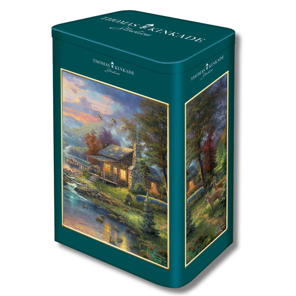 Thomas Kinkade Studios Puzzle 500 Teile "Nature's Paradise" in einer dekorativen Blechdose. Zeigt eine idyllische Waldhütte am Flussufer bei Sonnenuntergang.
