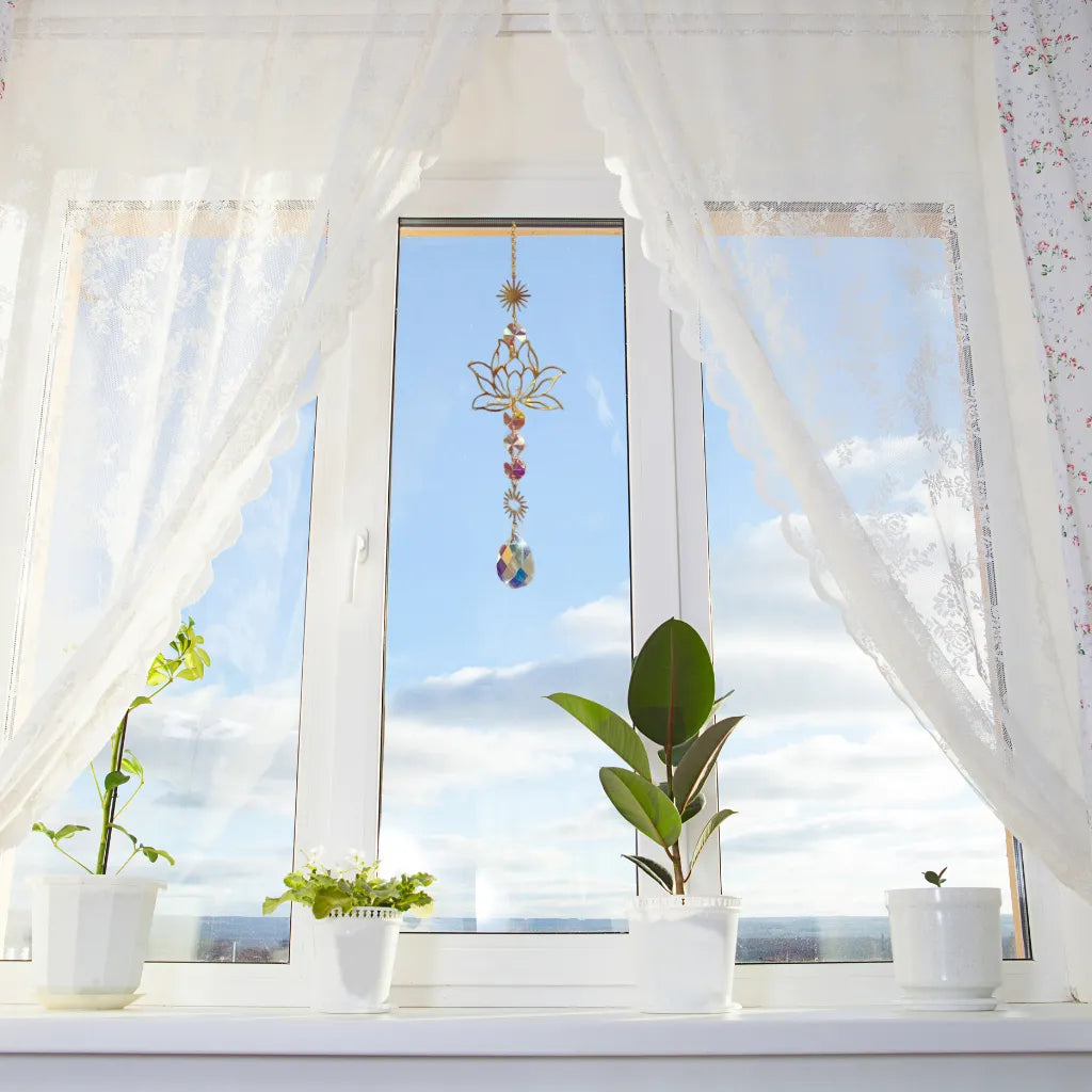 Elegante Sonnenfänger Kette mit goldenem Lotusmotiv am Fenster, reflektiert Sonnenlicht und bringt Glanz ins Zuhause.