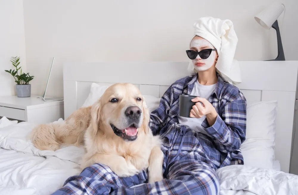 Frau entspannt mit Hund im Bett genießt Selfcare und Me-Time