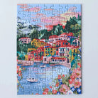 Das vollständig gelegte 99 Teile Piecely Minipuzzle "Lake Como". Eine leuchtende Darstellung des malerischen italienischen Sees mit farbenfrohen Gebäuden, Bergen und einem Segelboot im Wasser.