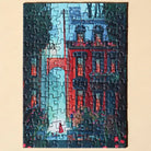 Fertig gelegtes Piecely Minipuzzle 99 Teile "Midnight Walk". Das Motiv zeigt eine nächtliche Straßenszene mit einem roten Haus, Bäumen und einer Frau im roten Mantel unter Straßenlaternen.