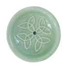 Nahaufnahme eines runden Keramik Räucherstäbchenhalters in sanftem Mintgrün, verziert mit einem harmonischen weißen Knotenmuster und einem zentralen Loch für Räucherstäbchen.