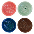 Vier runde Keramik Räucherstäbchenhalter in Korallrot, Mintgrün, Königsblau und Dunkelbraun, jeweils mit einem harmonischen weißen Knotenmuster und zentralem Loch, auf weißem Hintergrund präsentiert.