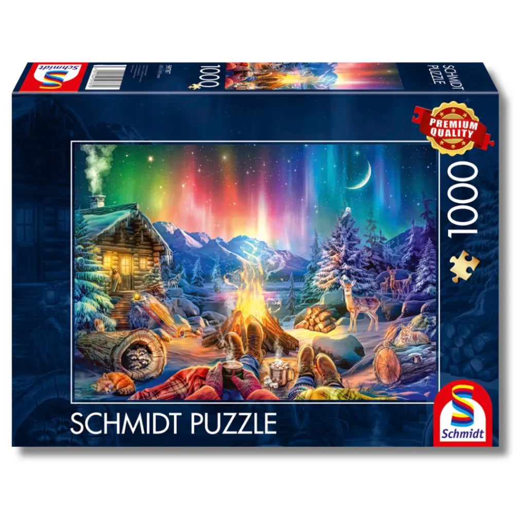Verpackung des 1000-Teile Schmidt Puzzles mit einem winterlichen Motiv: Leuchtende Polarlichter, eine gemütliche Blockhütte und zwei Personen am Lagerfeuer.