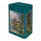 Thomas Kinkade Studios Puzzle 500 Teile "Nature's Paradise" in einer dekorativen Blechdose. Zeigt eine idyllische Waldhütte am Flussufer bei Sonnenuntergang.